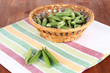 Green peas in wooden basket on napkin on table