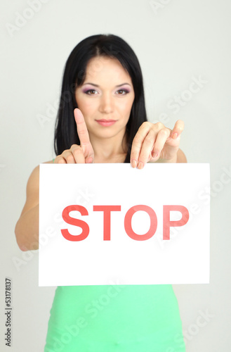 Photo: Girl showing stop sign on grey background Girl showing stop sign on grey background
