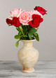 Beautiful bouquet of roses in vase on table on gray background