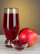 Glass of fresh garnet juice on table on gray background