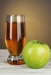 Glass of fresh apple juice on table on gray background