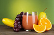 Glass of fresh juice on table on green background