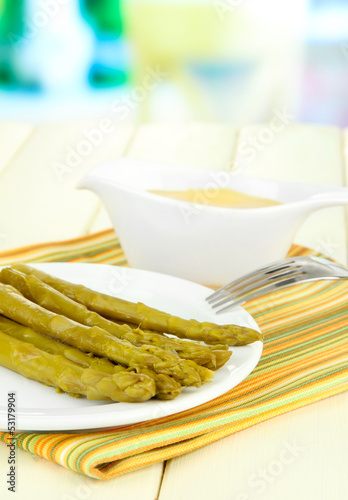 Photo: Asparagus on plate, on wooden table on bright background Asparagus on plate, on wooden table on bright background