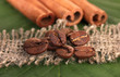 Photo: Coffee grains and cinnamon on sackcloth on green leafs close-up Coffee grains and cinnamon on sackcloth on green leafs close-up