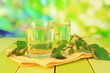 Glasses of birch sap on wooden table, on green background