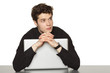 Pensive young businessman sitting at table looking to side