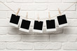 Photo: Blank photos hanging on a clothesline over brick wall background Blank photos hanging on a clothesline over brick wall background