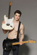 Muscular man with bare torso handing two electric guitars