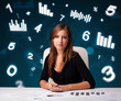 Young businesswoman sitting at desk with diagrams and statistics