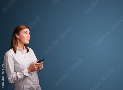 Photo: Young woman standing and typing on her phone with copy space Young woman standing and typing on her phone with copy space