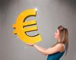 Beautiful girl holding a big 3d gold euro sign