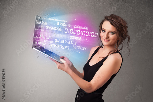 Photo: Casual woman holding laptop with exploding data and numers Casual woman holding laptop with exploding data and numers