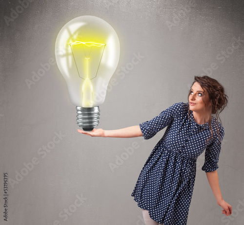 Photo: Beautiful lady holding realistic 3d light bulb Beautiful lady holding realistic 3d light bulb