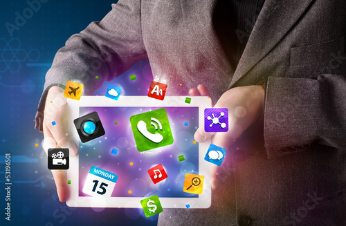 Photo: Businessman holding a tablet with modern colorful apps and icons Businessman holding a tablet with modern colorful apps and icons