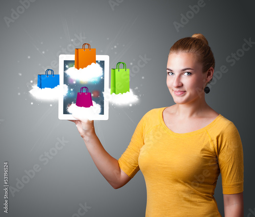 Photo: woman holding modern tablet with colorful shopping bags on cloud woman holding modern tablet with colorful shopping bags on cloud