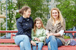 Photo: Two young women and little girl sit on bench Two young women and little girl sit on bench