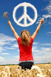 The girl in a wheaten field looks at peace symbol from clouds