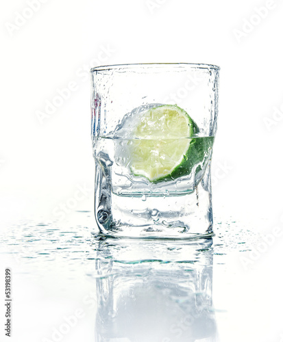 Photo: Vodka with lime in glass beaker, isolated on white Vodka with lime in glass beaker, isolated on white