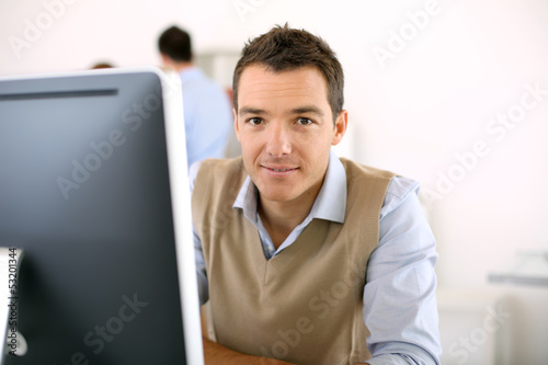 Photo: Man working in office in front of desktop computer Man working in office in front of desktop computer