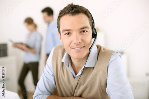 Photo: Portrait of consultant on the phone with headset Portrait of consultant on the phone with headset