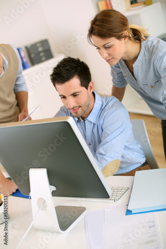 Photo: Workteam in office working on desktop computer Workteam in office working on desktop computer