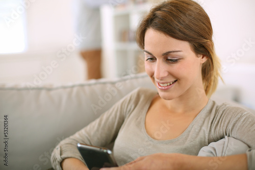 Photo: Young girl at home sending message with smartphone Young girl at home sending message with smartphone