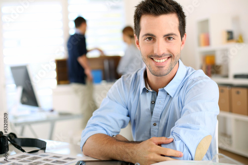 Photo: Portrait of cheerful man sitting in office Portrait of cheerful man sitting in office