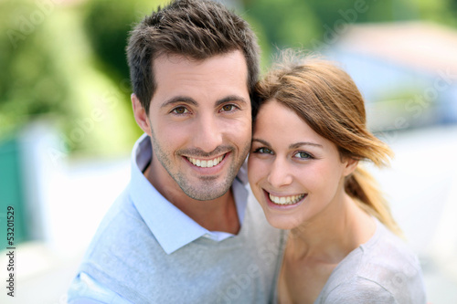 Photo: Cheerful couple standing in front of new house Cheerful couple standing in front of new house