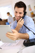 Cheerful man in office answering the phone