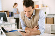Man in office sending message with smartphone