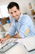 Smiling man in office working on digital tablet