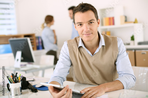 Photo: Handsome guy working with tablet in office Handsome guy working with tablet in office