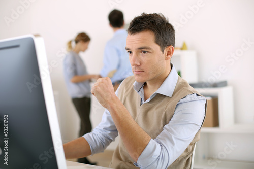 Photo: Man working in office in front of desktop computer Man working in office in front of desktop computer