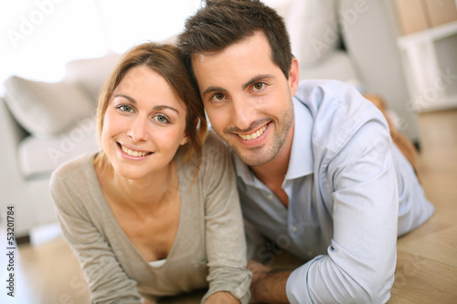 Photo: Cheerful couple laying on the floor at home Cheerful couple laying on the floor at home