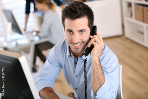 Photo: Smiling office worker talking on the phone Smiling office worker talking on the phone