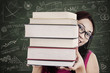Close-up female student bring stack of books in class
