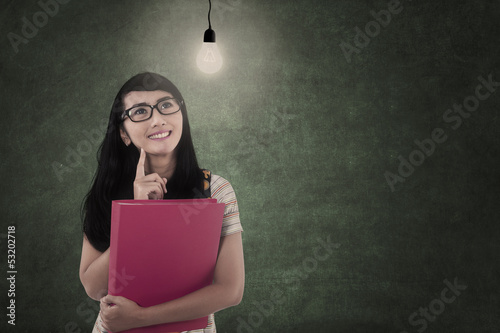 Photo: Asian student looking at lit bulb in class Asian student looking at lit bulb in class