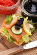 antipasto di crostini con salmone, verdure e uova di lompo