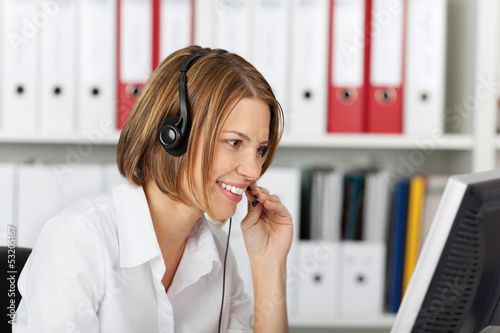 Photo: Serious smiling businesswoman talking on headset Serious smiling businesswoman talking on headset