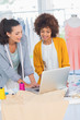 Foto: Cheerful fashion designers working on a laptop Cheerful fashion designers working on a laptop