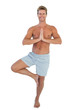 Foto: Cheerful man doing the tree pose Cheerful man doing the tree pose