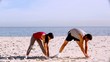 Sportsman and sportswoman stretching on the beach