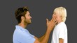 Man pressing inflated cheeks of his son on grey background