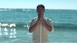 Handsome man practicing yoga on the beach