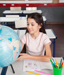 Foto: Schoolgirl Searching Places On Globe At Desk Schoolgirl Searching Places On Globe At Desk