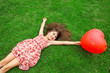 beautiful girl lying on the grass and holding a red ball in the