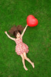 beautiful girl lying on the grass and holding a red ball in the