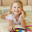 joyful little girl lying on the bed collects mosaic