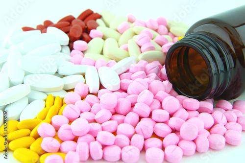 Photo: Closeup image of colorful pills and brown bottle Closeup image of colorful pills and brown bottle
