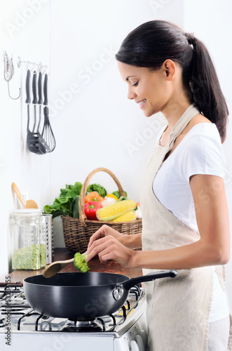Photo: Beautiful indian woman cooking in the kitchen Beautiful indian woman cooking in the kitchen